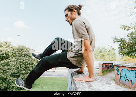 Young beautiful caucasian man doing parkour outdoor in the city in autumn - stunt, acrobat, trick concept Stock Photo