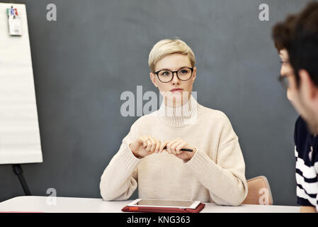 Young professional businesswoman engaged in discussion with colleagues in a boardroom meeting in a contemporary office Stock Photo
