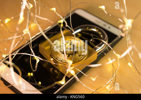 Bitcoin and padlock over a screen with a web of connected dot lights on the foreground Stock Photo