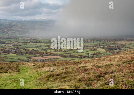 A rain shower drifts across the valley below the Clwydian range of hills near Moel Famau in North Wales. Wales, United Kingdom. Stock Photo
