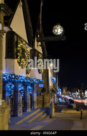 Christmas wreath decorations and lights on the Tolsey Museum at night. Burford, Cotswolds, Oxfordshire, England Stock Photo