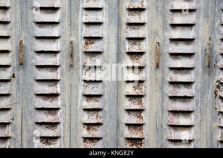 Rusty, peeling pastel coloured metal window shutter in Brittany, France Stock Photo