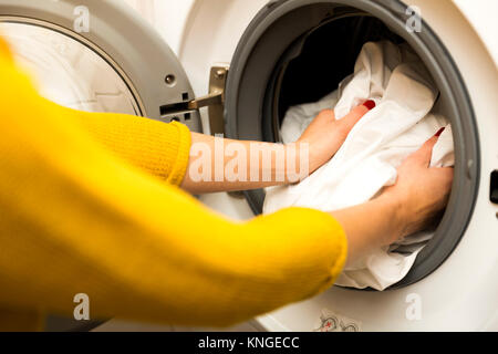 Woman hand loading dirty clothes in washing machine Stock Photo