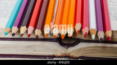 Colored pencils for painting at old books. Stock Photo