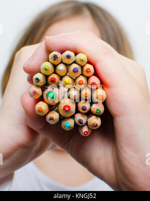 Colored pencils for painting in children's hands on a white background. Stock Photo