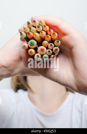 Colored pencils for painting in children's hands on a white background. Stock Photo