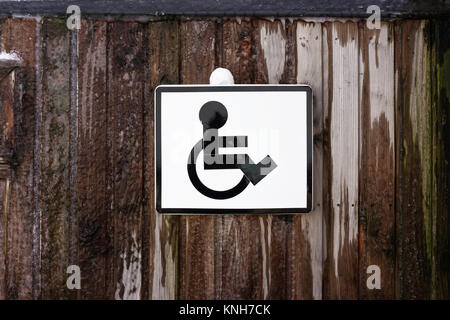 Parking access sign for disabled person on a wooden frozen wall. Icon of a disabled person on a wheelchair. Stock Photo