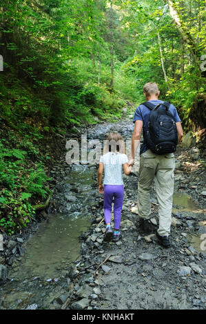 A man and a girl are walking up the mountain path. Stock Photo