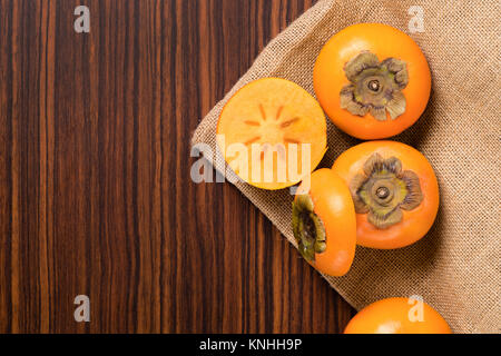 Persimmon fruit on rustic sack and wooden table Stock Photo