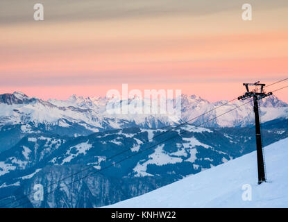 winter landscape in the Swiss Alps with a ski resort and chairlift in the foreground under a beautiful evening sky Stock Photo