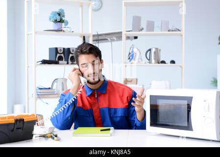 Young repairman fixing and repairing microwave oven Stock Photo