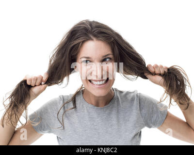 Angry woman having a bad hair day, she is pulling her messy and tangled hair Stock Photo