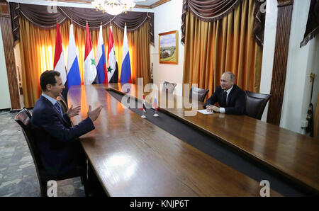 Russian President Vladimir Putin, right, meets with Syrian president Bashar al-Assad, left, during a visit to Khmeimim Air Base  December 11, 2017 in Latakia, Syria. Putin announced the withdrawal of most Russian forces from Syria following the war against the Islamic State. Stock Photo