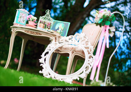 Retro styled chair, table and white carved frame. Pretty things, symbols of Alice in Wonderland Stock Photo