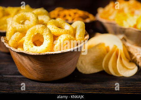 Close up of wooden plate with tasty corn snack near wooden plates with snacks on dark wooden desk. Food and beverages concept Stock Photo