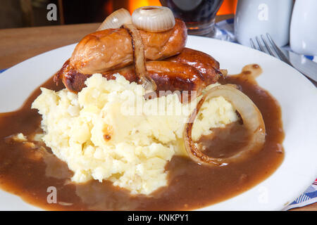 An English pub/restaurant dish of Sausage, Mashed potato and gravy topped with caramelized onion Stock Photo