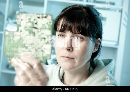 Electronics repair tech examines a curcuit board Stock Photo
