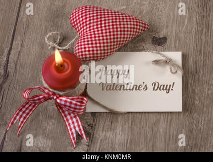 Greeting card "Happy Valentine" with burning candle and stuffed heart on wood Stock Photo