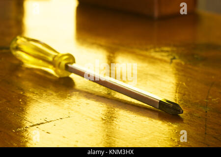 Horizontal photo of a yellow philips head screwdriver on a wood table yellow background Stock Photo