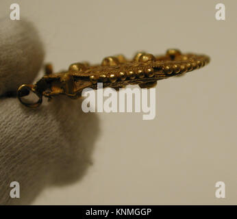 A medieval gold earring from the 11th–13th century with filigree and granulation decoration, originally set with stones, showing historical jewelry techniques. Stock Photo