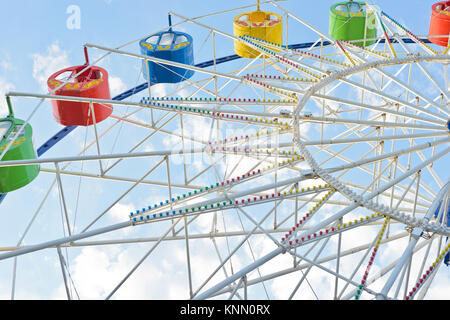 А part of white ferris wheel with colorful cabins against the backgroud of the blue sky with clouds Stock Photo