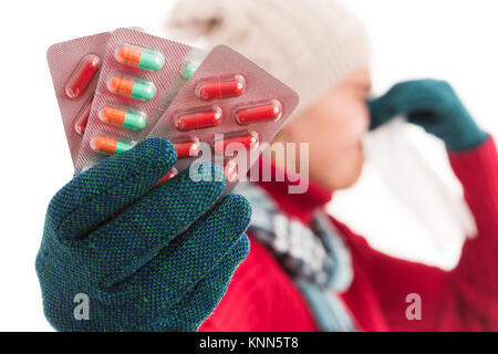 Sick cold woman blowing her nose and holding medicine tabletes isolated on white background Stock Photo