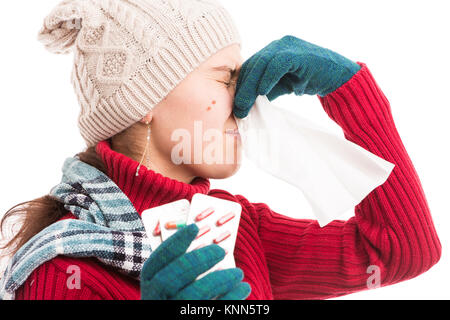 Warm dressed woman blowing her nose and holding medicine tabletes as cold influenza virus concept Stock Photo