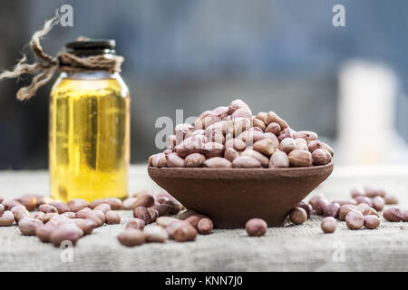 [Arachis hypogaea] Raw Groundnut in a clay bowl with groundnut oil on a gunny background.; Stock Photo