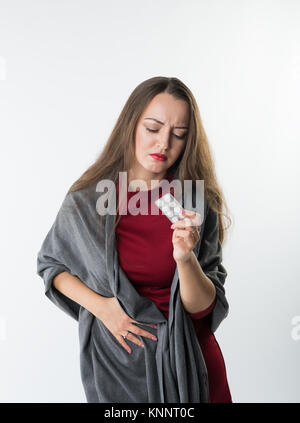 Woman in pain holds pills or drugs Isolated on a white background Stock Photo