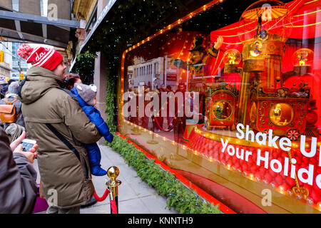 Street life, father holding baby looking at Saks Fifth Avenue Christmas Holiday window in downtown Toronto, Canada. Stock Photo