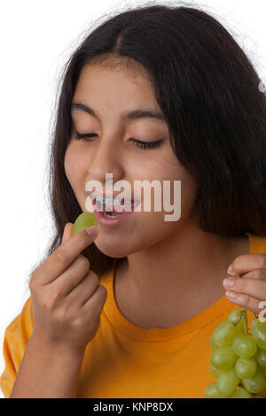 Teenage girl with dental braces eating healthy green grapes grapes Stock Photo