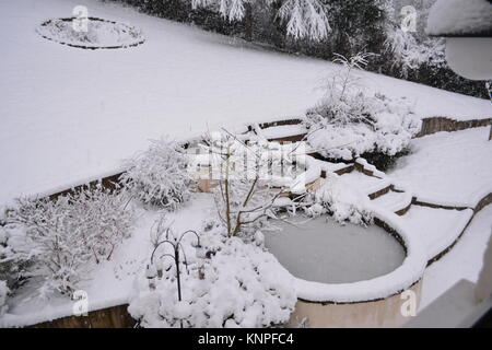 large circular ponds in snow and ice covered in garden after a heavy snow storm with small shrubs and bushes the doward south herefordshire england UK Stock Photo