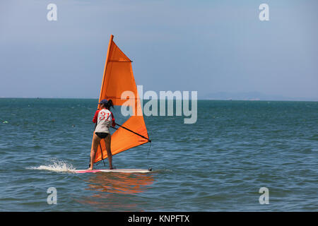 Young woman windsurfing with orange tarpaulin at sea Stock Photo