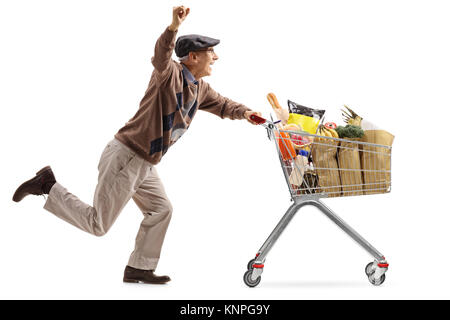 Joyful elderly man pushing a shopping cart filled with groceries and holding his hand up isolated on white background Stock Photo