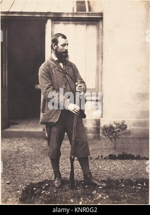 This portrait shows a man wearing hunting attire, including jacket, boots, and accessories, posed to display his appearance and gear. Stock Photo