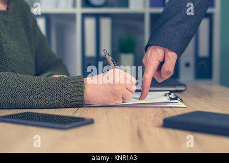 Boss giving orders and work tasks with assignment to be improved. Male hand pointing to female employee's paperwork. Stock Photo