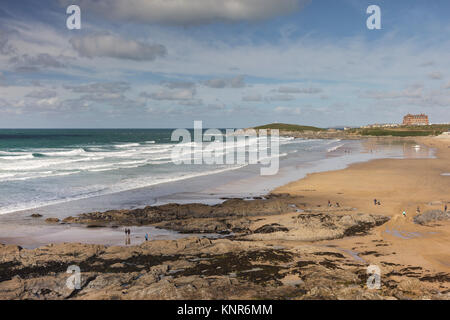 View across Fistral Beach in Newquay in Cornwall towards the Headland Hotel. Waves are breaking on the beach and surfers are in the water. Stock Photo