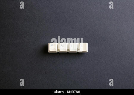 Mail word is written with computer keys button. Flat lay view from above on the table with computer keyboard keys buttons on a dark background. Stock Photo