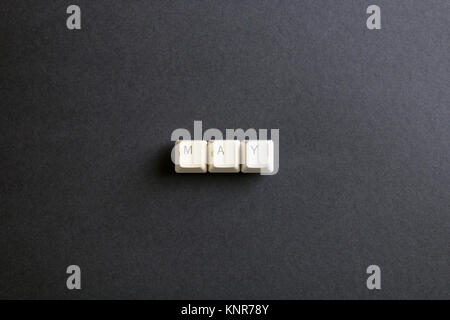 May month word is written with computer keys button. Flat lay view from above on the table with computer keyboard keys buttons on a dark background. Stock Photo