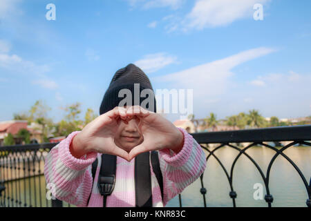 Asian little girl showing hand make heart shape with happiness in vacation travel, select focus on hands shallow depth of field, with copy space Stock Photo