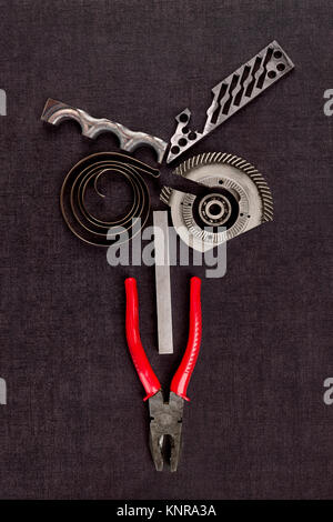 Screws, cogwheels and mechanical components on black surface from above. Stock Photo