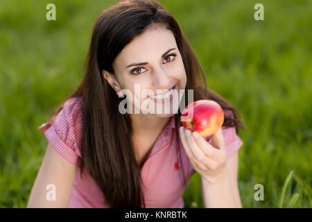 Junge Frau mit Apfel in der Wiese - woman with apple in meadow Stock Photo