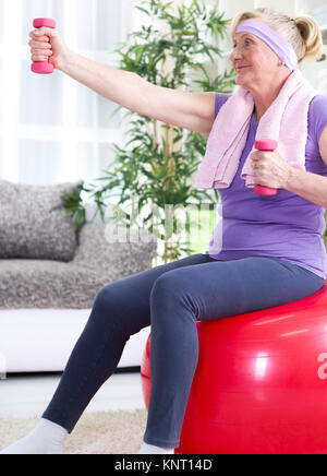 Senior woman at home exercising with dumbbell at home Stock Photo