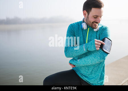 Sportsman using phone to listen to music while running and joggi Stock Photo