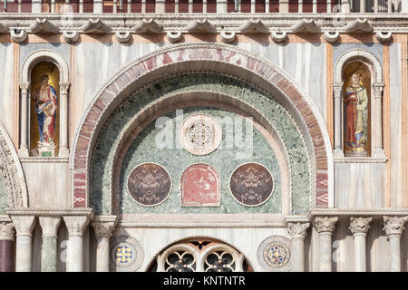 Architectural detail of the facade of Basilica San Marco, Venice, Italy showing inlaid stonework , carved capitals on columns and alcoves with golden  Stock Photo