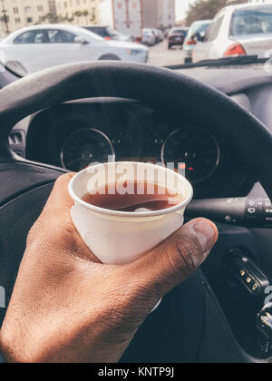 Man hold hot tea paper cup in car. Stock Photo