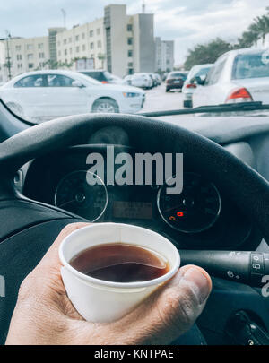 Man hold hot tea paper cup in car. Stock Photo