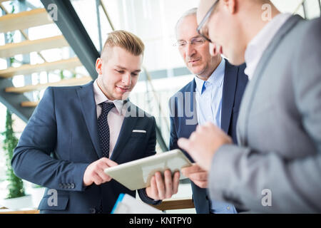 Handsome young businessman using digital tablet with colleagues in office Stock Photo