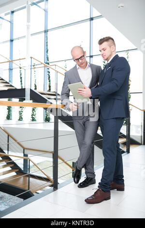 Full length of confident businessmen discussing over tablet computer in office Stock Photo