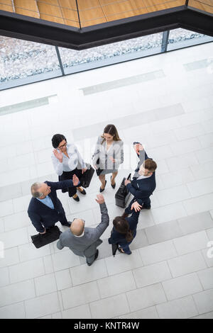 High angle view of male and female business executives giving high five to each other in office lobby Stock Photo